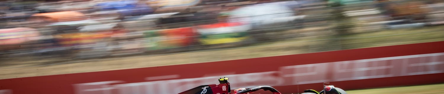 rød formel 1-racerbil fra Ferrari kjører fort på banen der den er avbildet